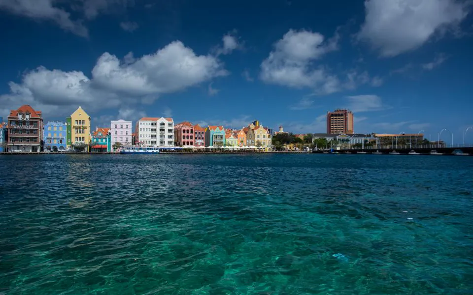 Willemstad desde la bahía: las casas de colores del Handelskade, el puente sobre el canal y el agua turquesa en primer plano